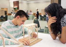 Blind teen smiles as he explains his engineering project to a fellow student