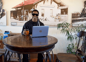 Student in coffee shop works on his laptop