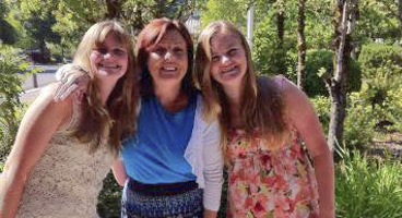 Three women smile together.
